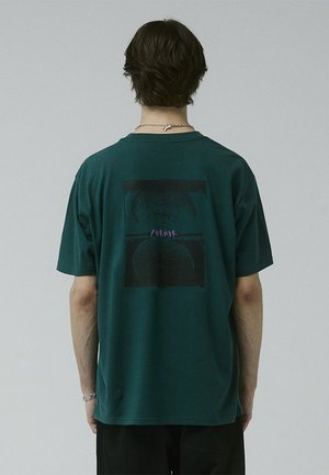 Dark green cotton t-shirt with a relaxed fit, featuring a graphic print in black and purple on the back, short sleeves, and round neckline.