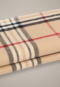 Beżowa tkanina w kratę z czarnymi i czerwonymi paskami, o miękkiej teksturze i tkanym wzorze. Dwie warstwy są złożone jedna na drugą.