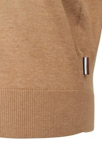 Hellbraun pullover aus weicher Stoff, mit geripptem Saum und einem kleinen dreifarbigen Akzentetikett an der Seite.