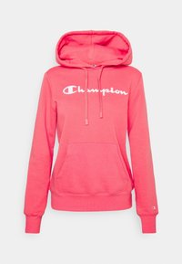 Růžová mikina vyrobená z měkké bavlny, s přední kapsou, šňůrkami a bílým logem "Champion" přes hruď. Dlouhé rukávy s žebrovanými manžetami.