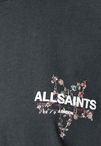 Tummanharmaa puuvillainen T-paita, jossa on vaaleanpunaisia ja sinisiä kukkaistikkauskuvioita sekä alle painettu rohkeilla valkoisilla kirjaimilla teksti "ALLSAINTS LONDON".