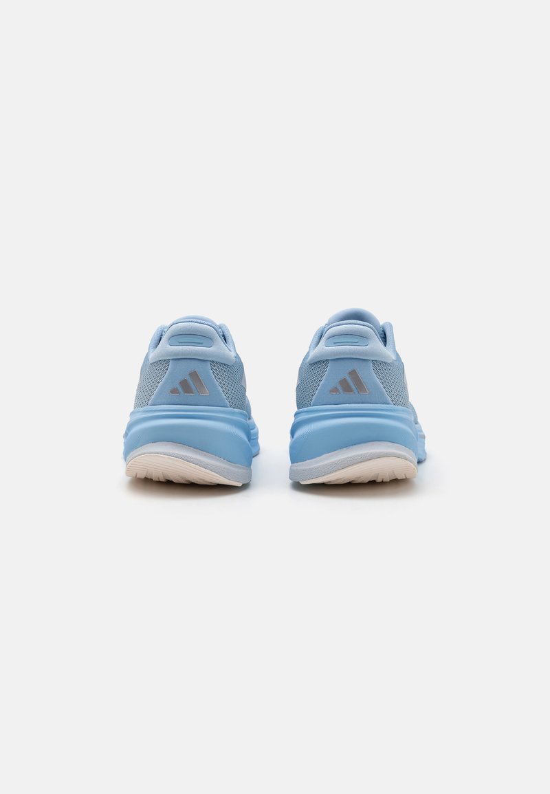 Zapatillas deportivas de color azul claro con parte superior de malla, collar acolchado y suela de goma blanca. Presenta un logo de tres franjas plateadas en el talón.