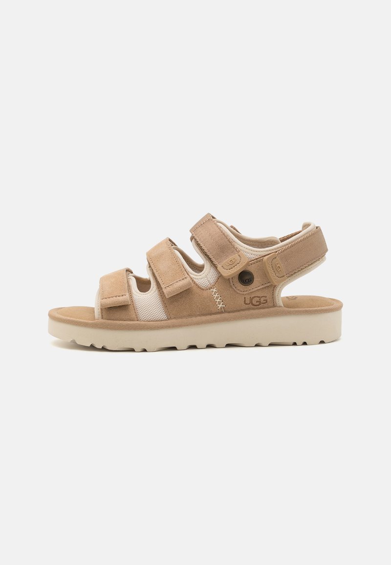 Beige sandaler med justerbare borrelåsreimer, et mykt skinn- og mesh-overside, og en lett gummisåle med mønster for grep.
