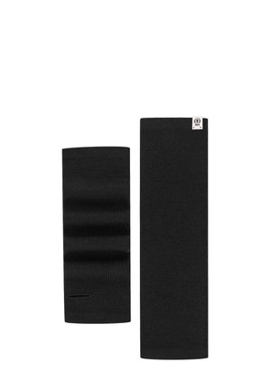 Two black knitted wrist warmers, one folded showing a thumb hole, the other flat with a small white label at the top edge.