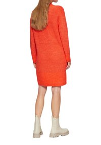 Oranges gestricktes Sweaterkleid mit langen Ärmeln, gerippter Textur am Saum und den Bündchen, kombiniert mit hellbeigen Ankle Boots.