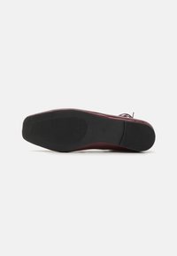 Burgundy leather shoe with a smooth upper, square toe, and a black rubber sole featuring horizontal ridges for traction.
