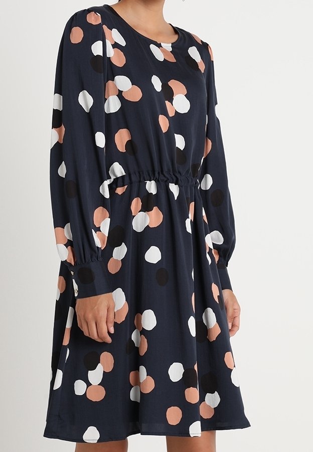Granatowa sukienka z długimi rękawami, zwężona w talii, z wielokolorowym, okrągłym wzorem w kropki w kolorze brzoskwiniowym, czarnym i białym.