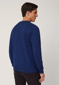 Maglione blu lavorato a maglia con finitura testurizzata, scollatura a girocollo e polsini e orlo a coste. Il retro presenta un colore uniforme senza decorazioni.
