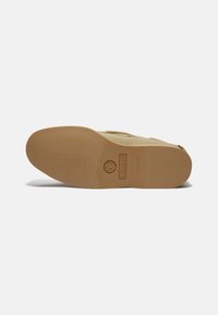 Ljust brunt skoprofil med en texturerad gummibotten, med Timberland-logotypen, som visar en icke-märkande design och släta kanter.