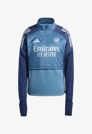 Jersey pullover de media cremallera en azul y marino, que presenta el logo "Emirates Fly Better", el escudo del Arsenal y tres rayas blancas en los hombros.