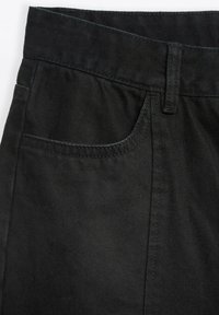 Czarne dżinsy w kolorze denim z średnim stanem, przednią kieszenią i widocznym ściegem. Gładka tekstura o lekkim połysku.