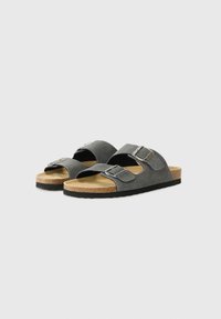 Sandale din suede gri închis cu două catarame argintii ajustabile, talpă din plută și talpă din cauciuc texturat negru. Design cu vârf deschis.