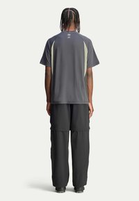 Grey short-sleeve athletic shirt with light grey accents; paired with loose black pants. Material appears lightweight and breathable.