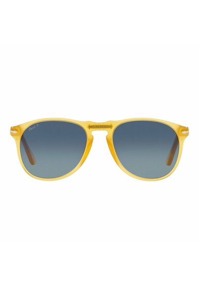 Occhiali da sole gialli traslucidi con lenti blu gradiente; presentano una forma classica wayfarer e dettagli marroni sulle aste.