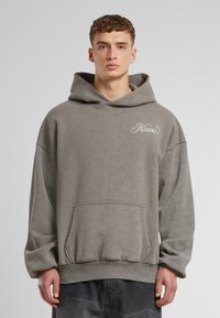 Gray cotton hoodie featuring a large front pocket, ribbed cuffs, and a drawstring hood. Small embroidered logo on the chest.