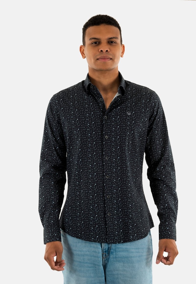 Chemise noire à manches longues avec un motif à pois de couleur bleu clair. Elle possède un col pointu et est fabriquée dans un tissu lisse.