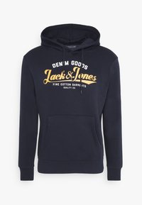 Námořnická modrá mikina vyrobená z bavlny, s přední kapsou, na které je bílo-žlutý grafický text "Jack & Jones" a "DENIM GOODS."