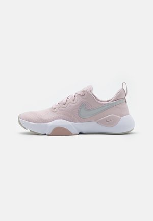 Chaussures de sport Nike en maille rose clair, avec un swoosh gris, un bout rond, un col rembourré et une semelle en caoutchouc blanche avec un accent rose.