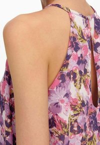 Top sin mangas de flores multicolores con detalle de espalda en forma de ojal, hecho de tela ligera en tonos rosa, morado y amarillo.