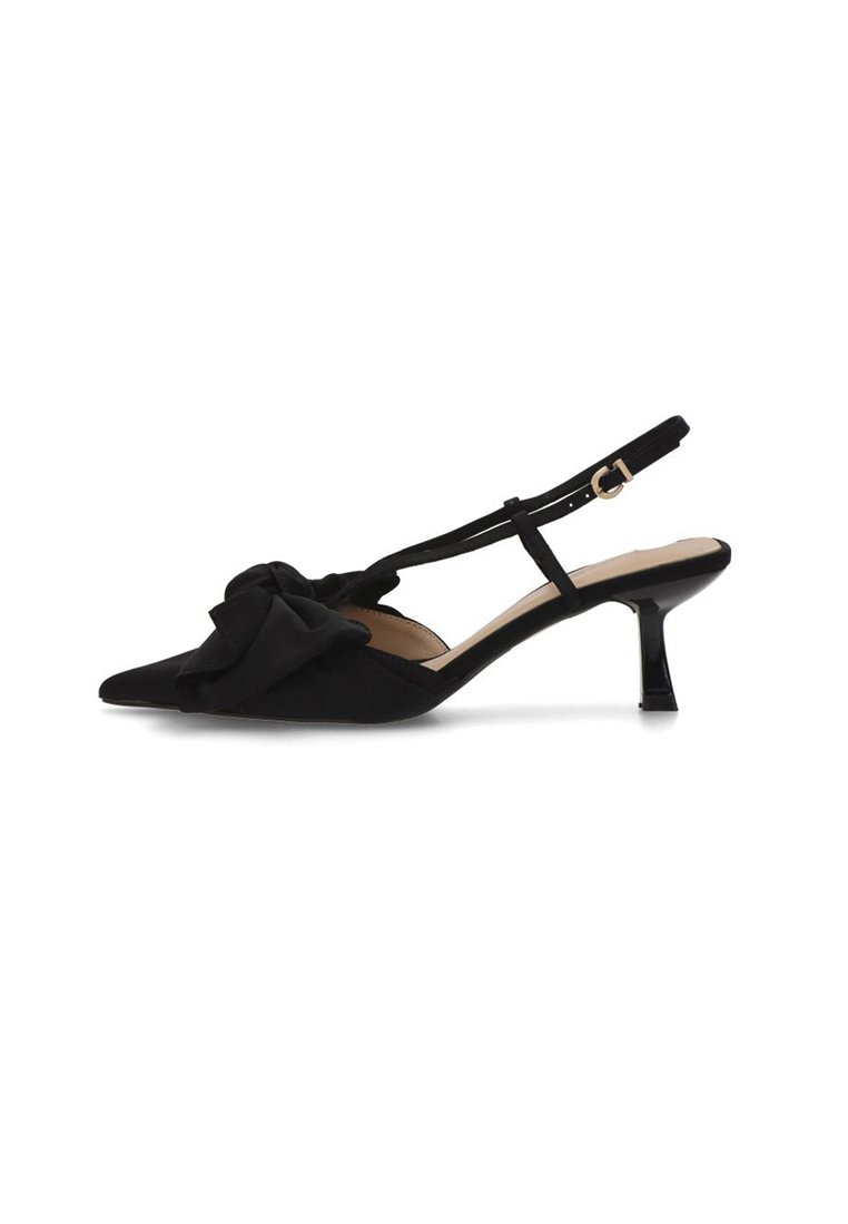 Zapato de salón negro con punta afilada y talón bajo tipo kitten, decorado con un lazo de tela en la parte frontal. Cuenta con una correa ajustable en el tobillo con hebilla dorada.