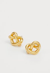 Gold-tone metal earrings with a knot design, featuring smooth surfaces and small clear crystal accents on each piece.