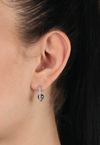 Söljörhängen i silver med en lila ädelsten, prydda med en rad små klara kristaller, som visar en elegant design och polerad yta.