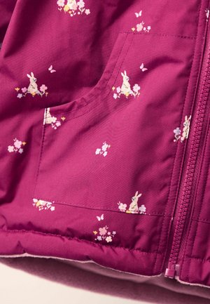 Fuchsia stofjakke med lynlås på forsiden, lommer og et gennemgående grafisk print af kaniner og blomster. Blødt, quiltet materiale.