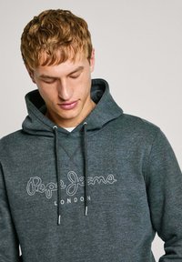 Felpa grigia scura realizzata in morbido tessuto, con cappuccio regolabile tramite coulisse e un logo ricamato bianco "Pepe Jeans London" sul davanti.