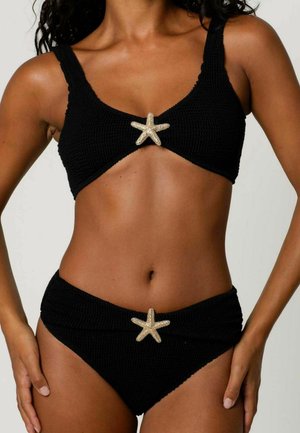 Ensemble de bikini noir en tissu texturé ; le haut présente un accent en étoile de mer dorée au centre, détail assorti sur le bas taille haute.