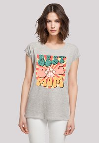 Grijze t-shirt met korte mouwen, voorzien van een kleurrijke "Beste Hond Mama" graphic met een pootafdruk, een gebogen ontwerp en vetgedrukte tekst in verschillende kleuren.