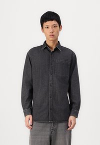 Black denim shirt with long sleeves, button-up front, and single chest pocket. Contrast stitching details and relaxed fit.