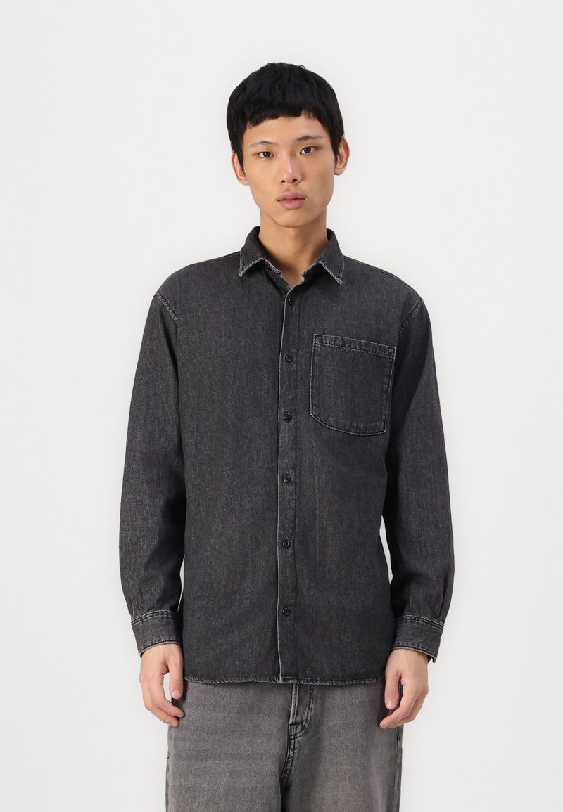 Black denim shirt with long sleeves, button-up front, and single chest pocket. Contrast stitching details and relaxed fit.