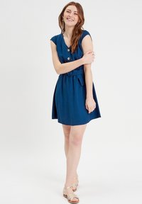 Navyblaues Kleid mit V-Ausschnitt, kurzen Ärmeln, Knopfleiste und Taillenband. Glatter Stoff, oberhalb des Knies in Länge und mit ausgestelltem Rockdesign.