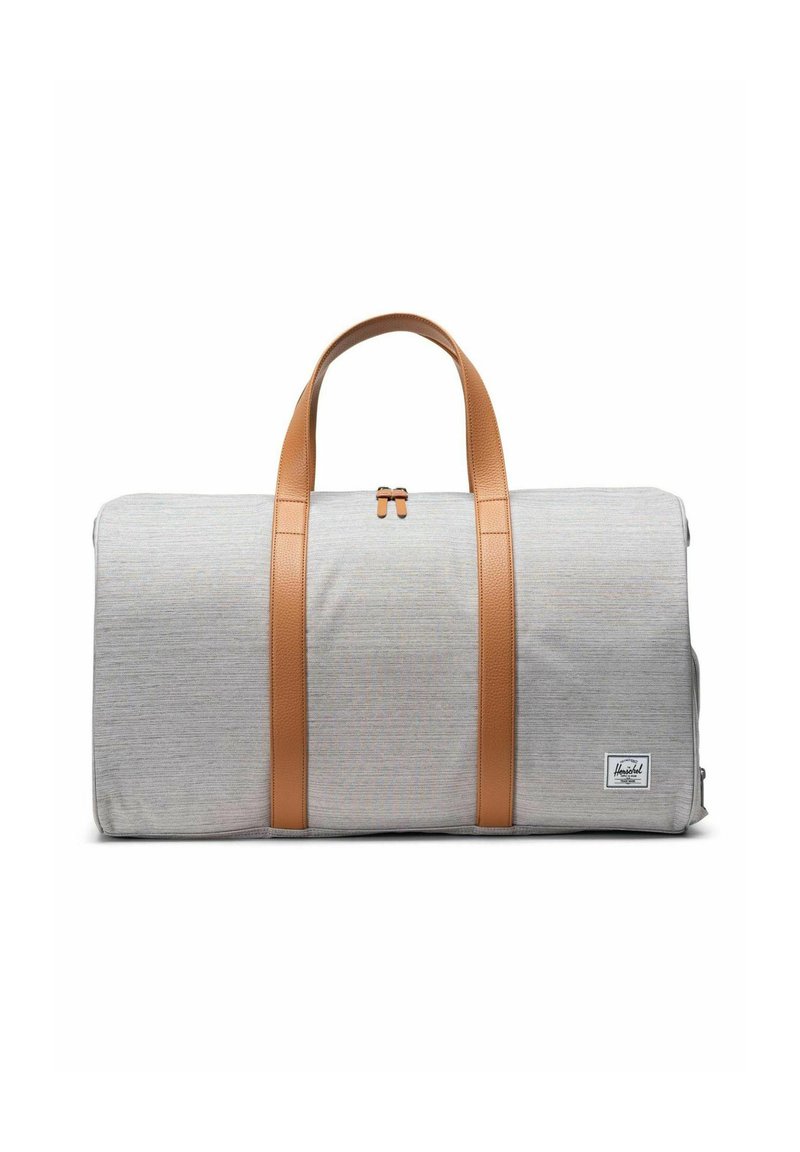 Sac de sport en tissu gris avec des poignées et des accents en cuir beige. Il dispose d'une fermeture éclair et d'un petit patch logo sur le côté.