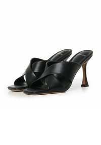 Mule con tacco aperte nere presentano cinturini incrociati in pelle, un design elegante e un tacco a stiletto distintivo con base rettangolare.