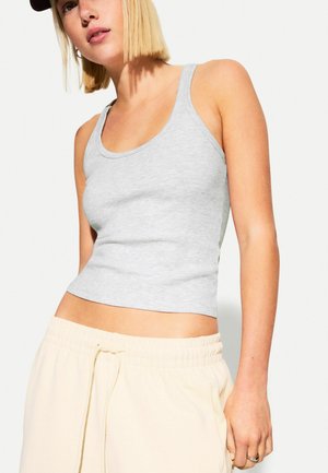 Gray ribbed tank top with a fitted design, scoop neck, and a cropped length, paired with light beige sweatpants featuring an elastic waistband.