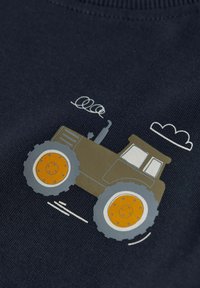 Námořnická bavlněná látka se grafickým motivem hnědého traktoru s oranžovými koly a bílými mraky, podrobně zpracovaná jemnými lince pro znázornění pohybu.