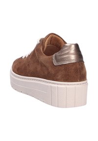 Bruine suède sneakers met witte veters, een gestructureerde witte zool, en een metallic bronzen accent op de hiel. Ronde neus en laag profiel ontwerp.