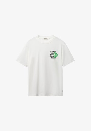 Camiseta blanca de manga corta con pequeño texto negro "SHIWI the sunshine brand" y gráfico de coral verde en el pecho izquierdo.