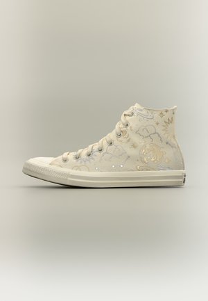 Beige højt sneaker med himmelske motiver inklusive stjerner, planeter, skyer og stjernebilleder i lyse toner på det tekstile overmateriale.