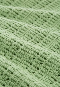 Helles grünes Häkelgewebe mit einem strukturierten Gittermuster und erhabenen Stichen, das ein weiches und detailliertes Aussehen verleiht.