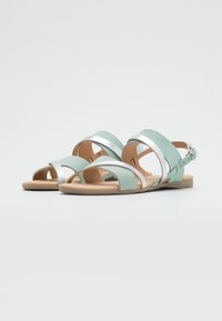 Mint green sueden sandaalit, joissa on hopeiset metalliset yksityiskohdat, avointoisen malli, leveät hihnat, säädettävä nilkk buckle ja beige kumipohja.