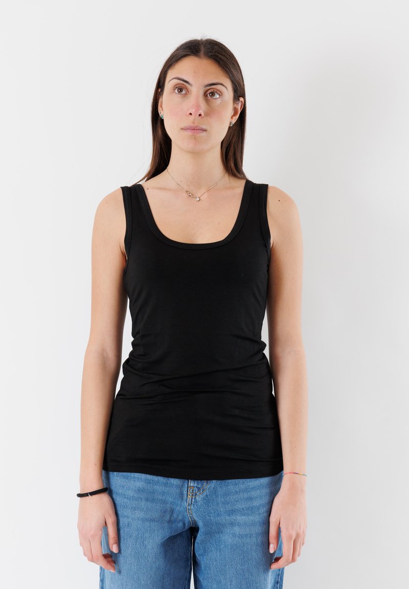Top nero senza maniche con scollo tondo, design aderente e tessuto morbido. Abbinato a jeans in denim blu chiaro con vestibilità comoda.