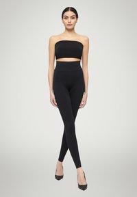 Top corto nero senza spalline e leggings a vita alta realizzati in tessuto morbido ed elastico; design elegante con texture liscia e silhouette aderente.