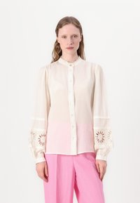 Cream-colored blouse with a high collar, buttons, and long, puffed sleeves featuring floral embroidery and a pink gradient at the hem.