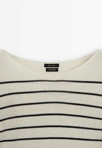 Maglione in cotone con scollatura ampia, caratterizzato da strisce nere orizzontali su uno sfondo crema. Le etichette indicano "100% Cotone, Prodotto in Cina."