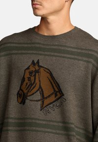 Trui van gebreide stof in olijfgroen met een bruine paardenafbeelding en zwarte omlijningen; met horizontale strepen in groen en grijs.