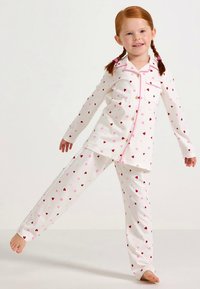 White cotton pajama set featuring a button-down top with a pocket and printed red and pink hearts, complemented by matching pants.