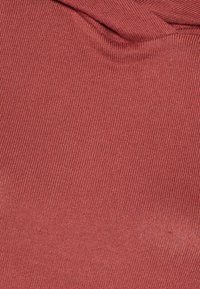 Roter gerippter Stoff mit glatter Textur, der oben leichte Raffung aufweist und somit eine weiche Drapierung erzeugt.