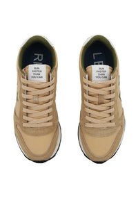 Scarpe sportive color beige chiaro con una tomaia in tessuto liscio e dettagli in suede. Presentano lacci crema e un colletto imbottito. Il testo sulla linguetta recita "CORRI PIÙ VELOCE DI QUANTO PUOI."